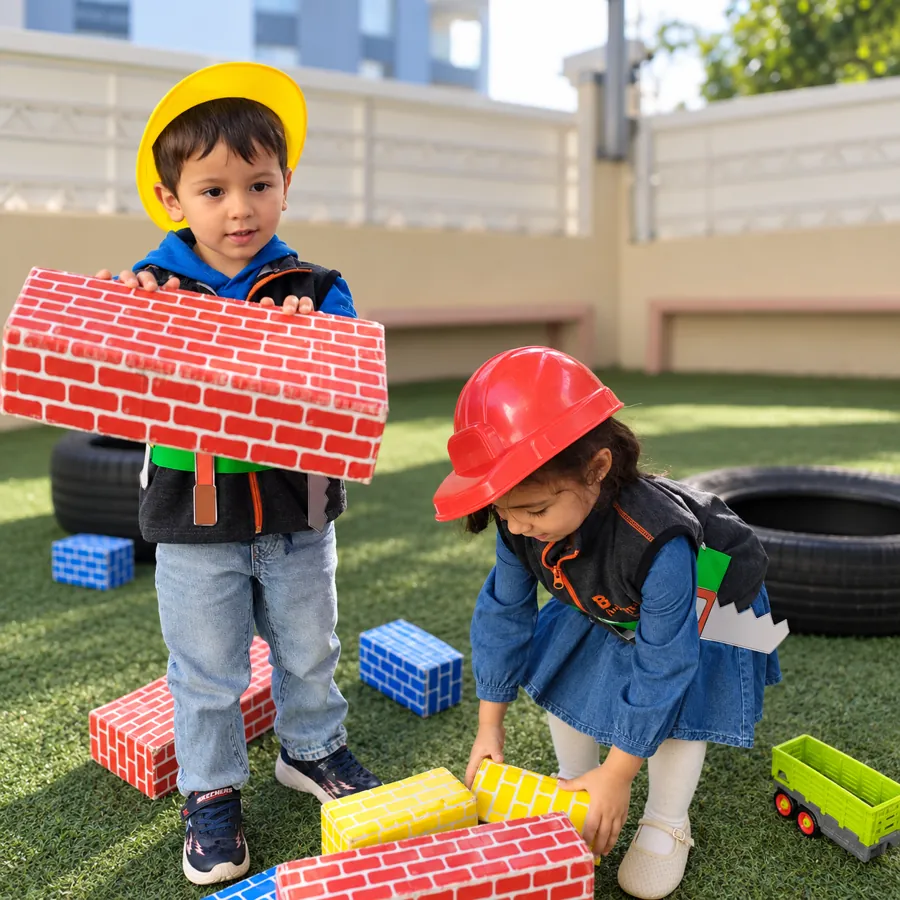 Deux enfants jouant aux bâtisseurs avec des briques en carton dans la cour de la crèche B.smart