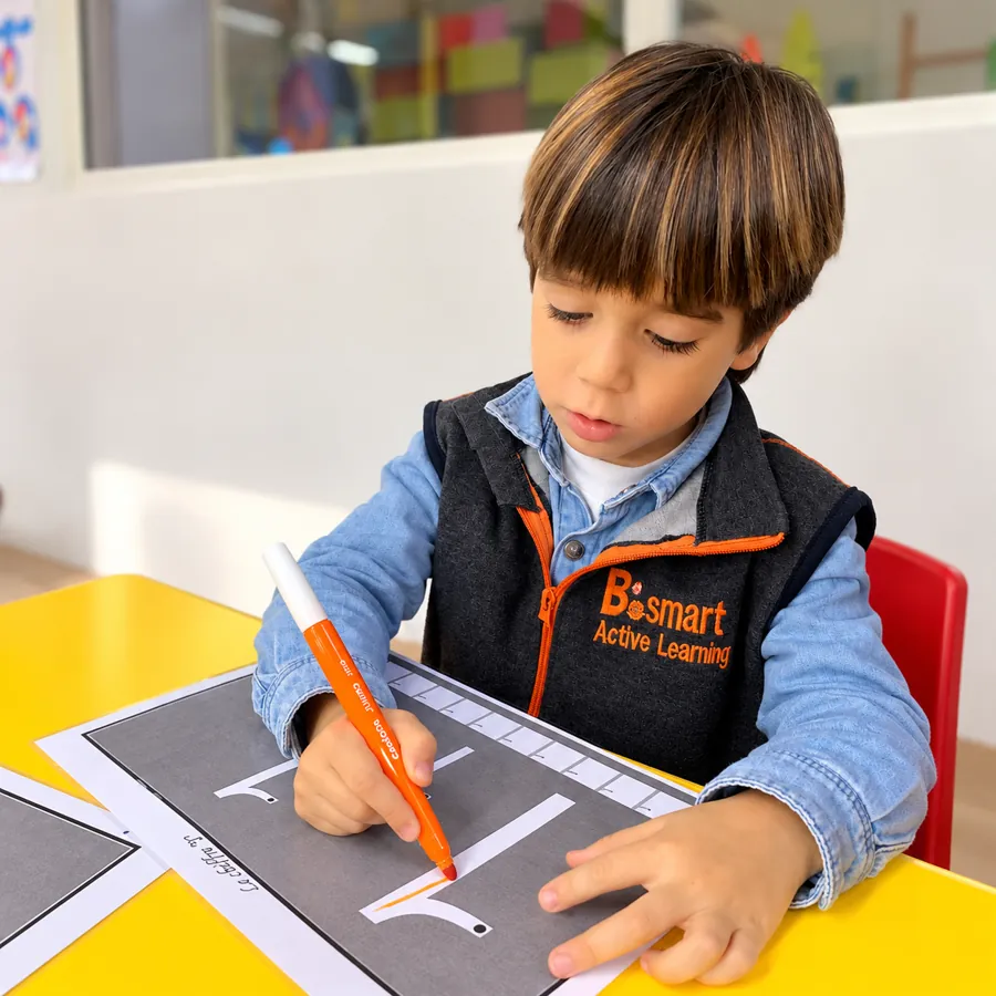 Enfant de Pre-K traçant des lettres au feutre à la crèche B.smart