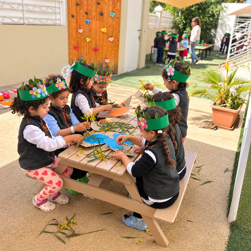 Enfants avec des couronnes de fleurs réalisant un collage nature en plein air