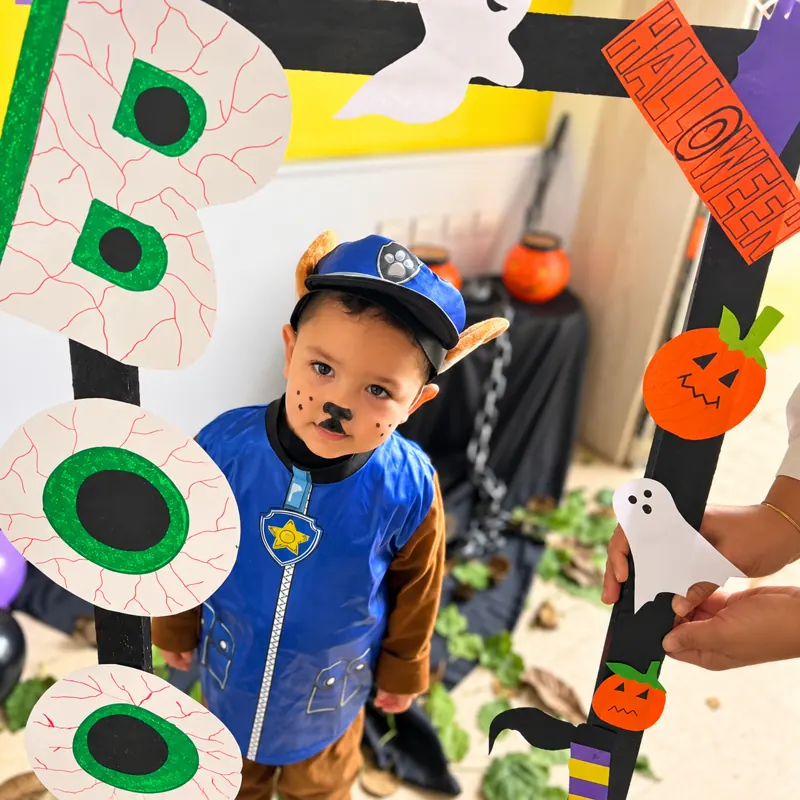 Enfant déguisé posant dans le cadre photo d'Halloween à la crèche B.smart