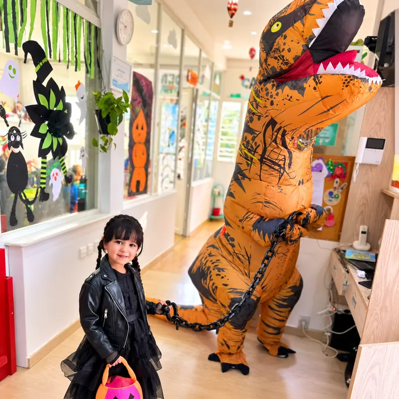 Fillette déguisée pour Halloween à côté d'un dinosaure gonflable à la crèche B.smart