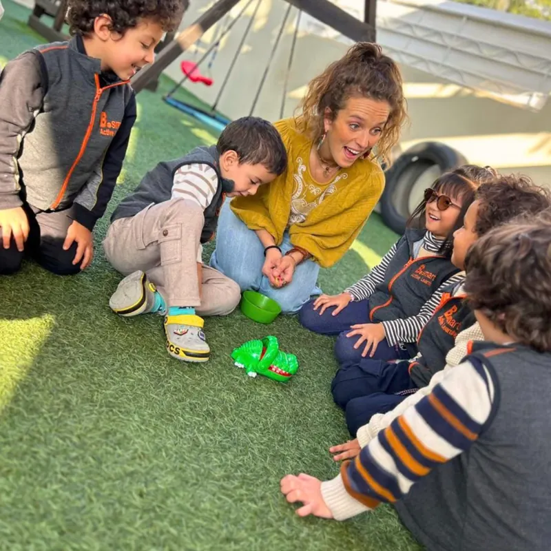 Éducatrice et enfants jouant au jeu du crocodile dans le jardin de la crèche B.smart