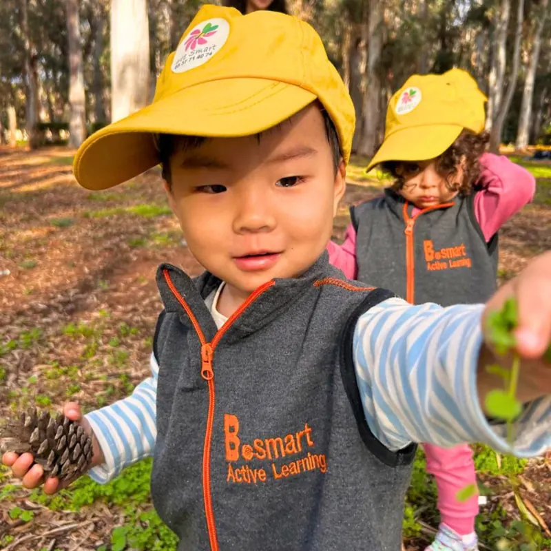 Enfant montrant une pomme de pin lors d'une sortie nature avec la crèche B.smart