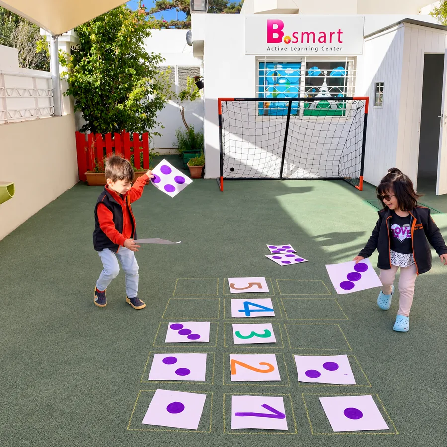 Enfants jouant à une marelle des chiffres dans la cour de la crèche B.smart à Hay Riad